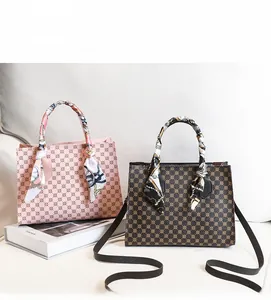 Detail of printed ladies handbags in pink and brown with decorative silk handle scarves