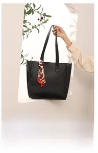 Detail of a textured black tote bag with a colorful silk scarf on slim shoulder straps