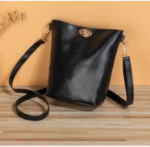 Détail d'un sac seau en cuir noir avec un fermoir tournant doré et une bandoulière chic