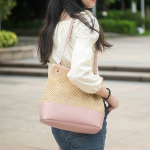 Women's woven straw tote bag with pink faux leather trim and metallic eyelet details