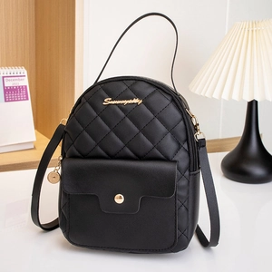 Mini black quilted backpack with gold logo and convertible straps on a white table