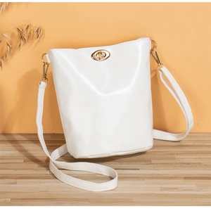 Détail d'un sac seau blanc avec un fermoir tournant doré et une bandoulière réglable