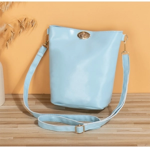 Détail d'un sac seau bleu clair avec fermoir rotatif doré et bandoulière ajustable