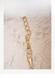 Detail of a bright gold chain shoulder strap with secure metal swivel lobster clasps
