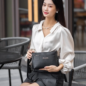 Quilted black leather shoulder bag with gold logo and crossbody strap for outdoor travel