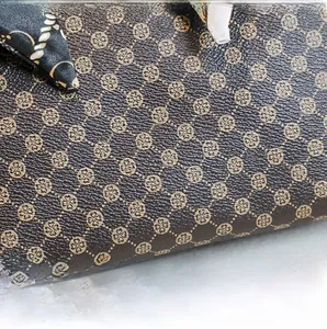 Macro shot of dark brown lychee texture leather with vintage clover print and silk scarf tie