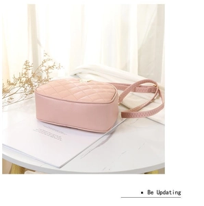 Detailed view of pale pink quilted faux leather camera bag with adjustable shoulder strap