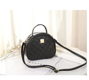 Detail of black quilted leather shoulder bag with gold metal plaque and top handle