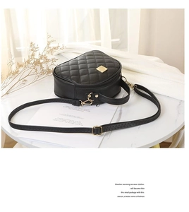 Macro detail of black quilted leather crossbody bag with golden square buckle and texture