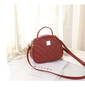 Detail of red quilted semi-circle handbag with diamond lattice pattern and top handle