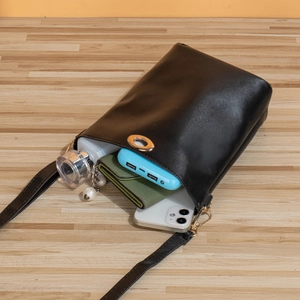 Sac seau bandoulière noir en cuir avec fermoir doré montrant le rangement interne