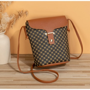 Close-up of brown vintage patterned crossbody bucket bag with leather flap on wooden table
