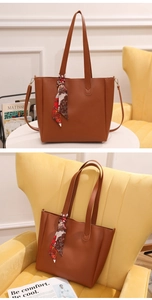 Detail of a brown PU leather tote bag with a decorative floral silk scarf on the handle