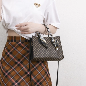 Brown printed handbag with silk scarf handle and long shoulder strap in side view