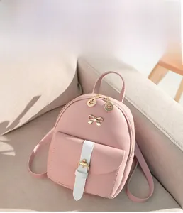 Detail of pink PU leather backpack featuring golden bow accent and leaf zipper pull