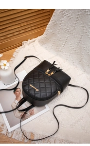 Gros plan du sac à dos noir matelassé avec fermeture éclair dorée et logo en métal