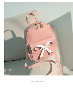 Détail d'un mini sac à dos en cuir PU rose avec nœud blanc et fermeture éclair dorée