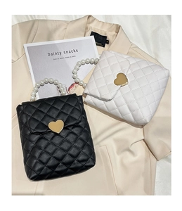Détail de mini sacs matelassés avec fermoirs cœur et anses élégantes en perles en noir et blanc