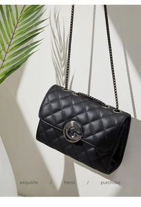 Détail d'un sac matelassé noir avec boucle argentée G et ombre élégante de feuille de palmier