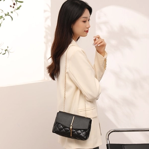 Sac bandoulière matelassé avec frange dorée sur mannequin en tailleur blanc