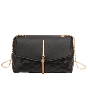 Sac bandoulière matelassé noir élégant avec pompon doré sur fond blanc pur