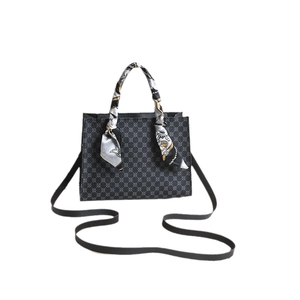 Patterned tote bag with black leather handles and decorative silk scarf detail