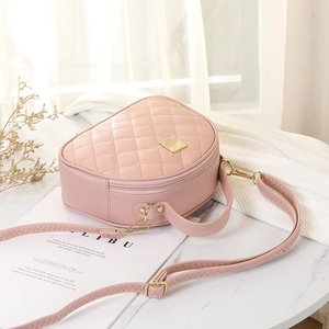 Pink quilted semi-circle handbag with gold hardware and adjustable strap in lifestyle setting