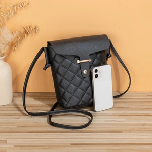 Classic black quilted crossbody bag with gold buckle and leather strap on a wooden table