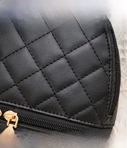 Gros plan sur la texture en cuir noir matelassé et la fermeture éclair dorée du sac à dos