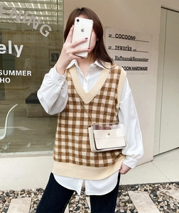 Photo de rue d'une femme portant un pull sans manches à carreaux et un sac bandoulière