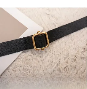 Détail de la bandoulière réglable en cuir noir avec boucle dorée et texture grainée