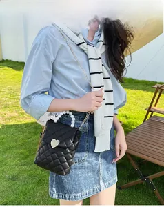 Détail du mini sac matelassé noir avec fermoir cœur et poignée élégante en perles