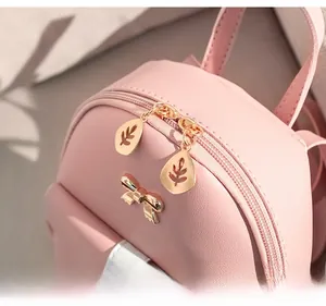 Detail of pink PU leather mini backpack featuring double zippers and golden bow charm