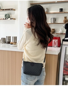 Crossbody small square bag with gray circular pattern worn over a knit sweater