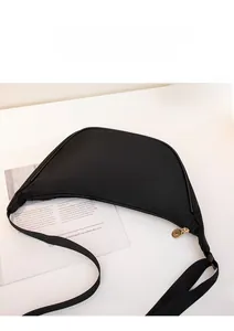 Close-up of a black crescent nylon chest bag with gold zipper and adjustable strap