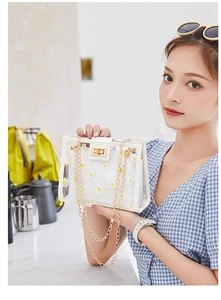 Detail of transparent PVC crossbody bag with white daisy print and gold chain strap
