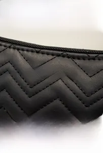 Detail of waterproof quilted leather bag with golden logo and scratch-resistant texture