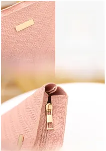 Detail showing pink woven texture, polished gold hardware, and metal zipper closure