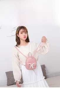 Gros plan d'un mini sac à dos rose avec nœud blanc porté par un mannequin en style