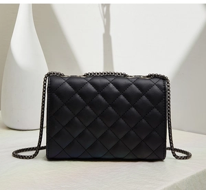 Détail du sac à bandoulière en cuir noir matelassé avec une chaîne en métal gris foncé