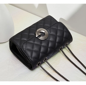 Détail du cuir matelassé noir classique avec fermoir métallique argenté et bandoulière chaîne