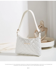 Detail of white quilted faux leather texture and gold logo on small shoulder bag