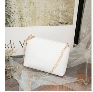 Detail of white PU leather crossbody bag with elegant gold chain strap on mesh fabric