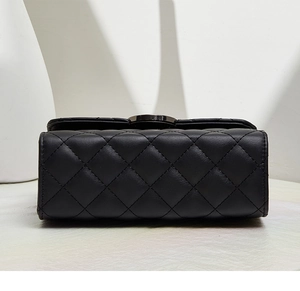 Détail de la base en cuir matelassé et des coutures fines d'un sac à chaîne noir