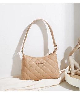 Close-up of beige quilted shoulder bag featuring premium texture and gold logo detail