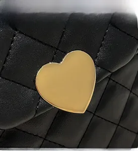 Vue détaillée du cuir matelassé noir avec un fermoir en métal doré en forme de cœur