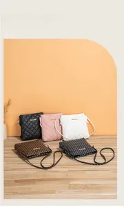 Detail view of five quilted and printed crossbody bags in various colors on wooden floor