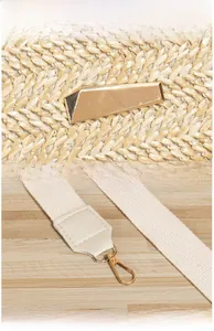 Détail du sac en paille avec ferrures dorées et poignées en sangle tissée blanc cassé