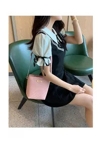 Pink bucket bag with textured embossing and golden metal hardware shown on a model