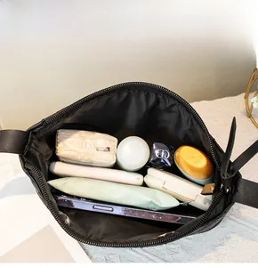 Interior view of black embroidered crossbody bag showing large storage capacity for cosmetics